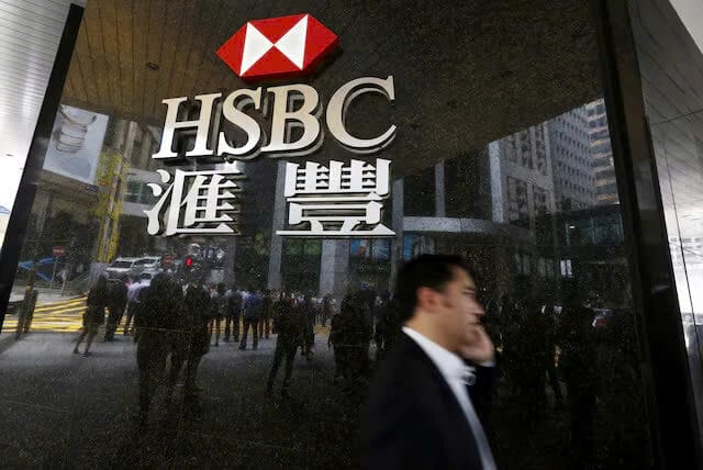 Một người đàn ông đi ngang qua logo của HSBC bên ngoài một chi nhánh tại khu trung tâm tài chính ở Hồng Kông, Trung Quốc ngày 2 tháng 6 năm 2015.