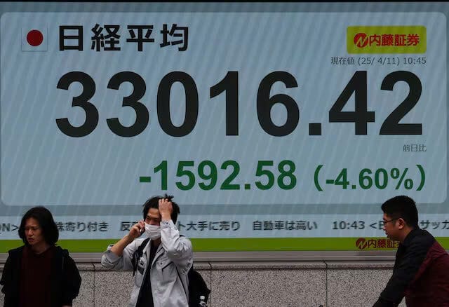 Mọi người đi ngang qua màn hình điện tử hiển thị chỉ số trung bình cổ phiếu Nikkei của Nhật Bản bên ngoài một công ty môi giới ở Tokyo, Nhật Bản, ngày 11 tháng 4 năm 2025.Thương mại