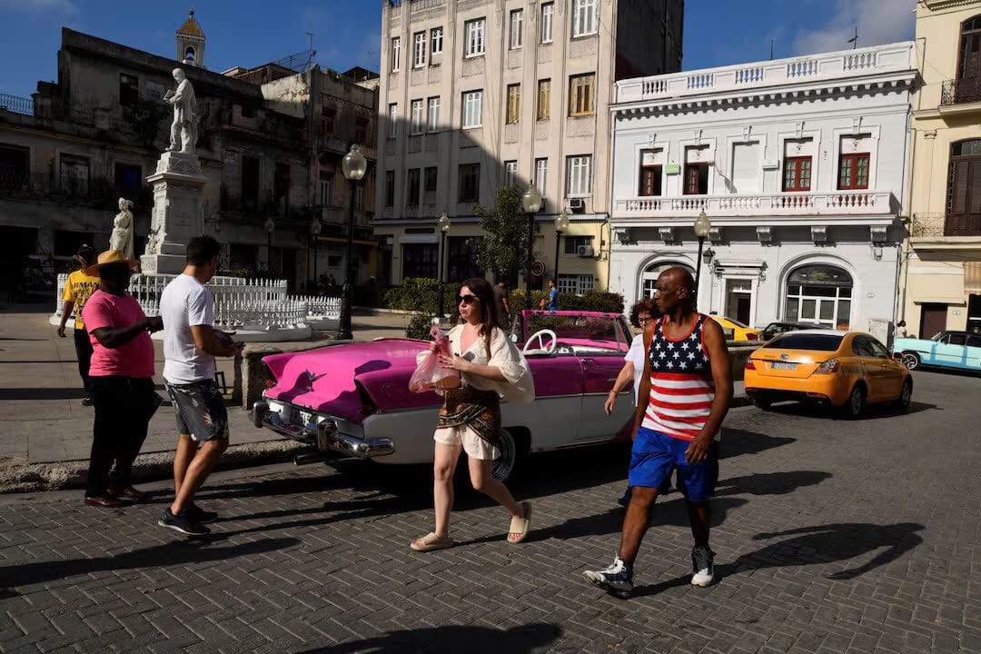 Một người đàn ông mặc áo phông có màu cờ Hoa Kỳ đi ngang qua khách du lịch ở trung tâm thành phố Havana, Cuba, ngày 30 tháng 4 năm 2025